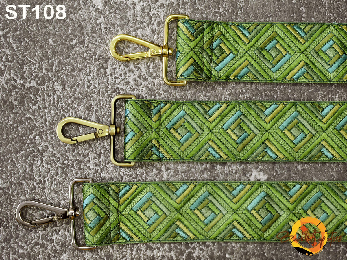 three green and blue patterned straps with metal buckles, arranged side by side on a textured surface.