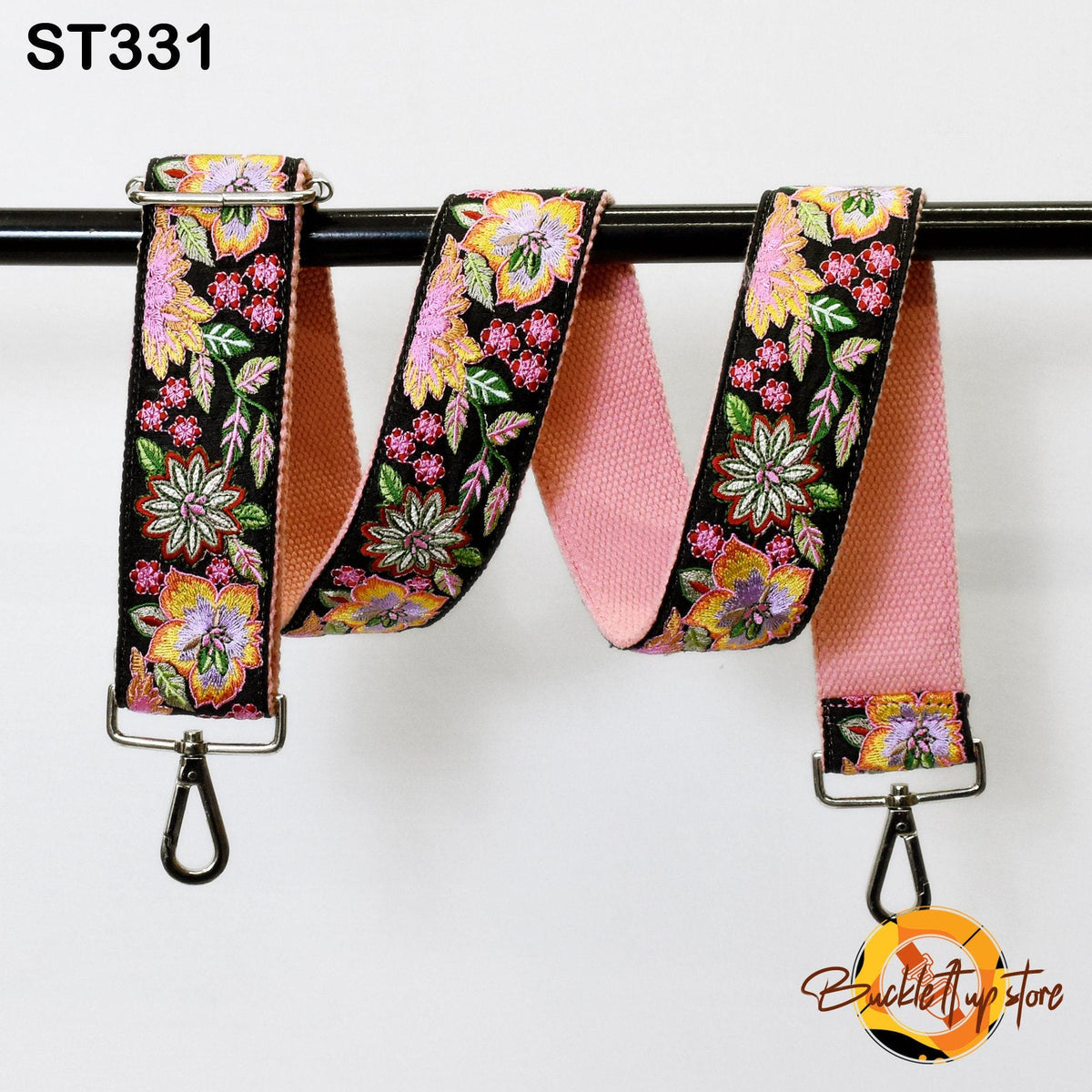 A floral-patterned pink strap with a metal hook attached, hanging from a black metal hook.
