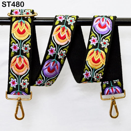 A colorful, embroidered strap with floral patterns in various shades of red, yellow, green, and purple. The strap is hanging from a black metal hook, with two gold metal hooks attached to the ends.