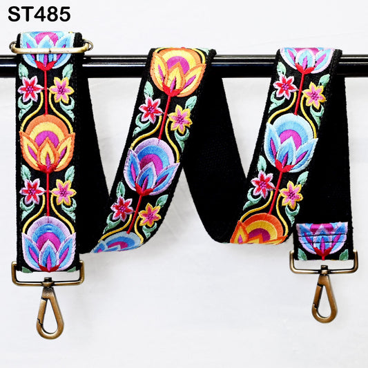 A colorful, embroidered strap with a floral pattern, hanging on a black metal hook.