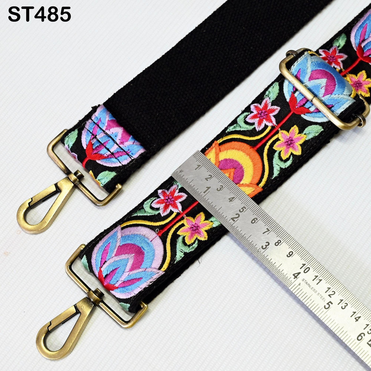 a colorful, patterned strap with a metal ruler placed on top of it, indicating the strap's length.