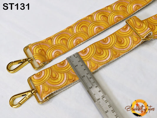 a gold-colored strap with a repeating pattern of circles and swirls, placed on a white surface. A ruler is placed next to the strap, indicating its size.