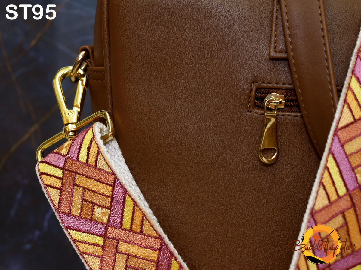 a close-up view of a brown leather handbag with a gold zipper pull and a colorful strap.
