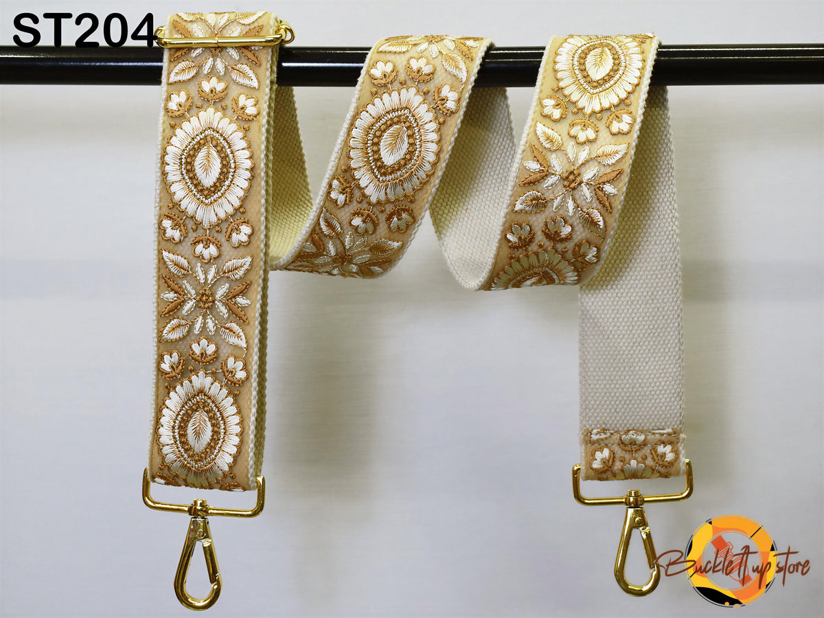 a pair of gold-colored, embroidered straps hanging on a black bar.