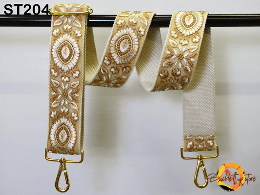 a pair of gold-colored, embroidered straps hanging on a black bar.