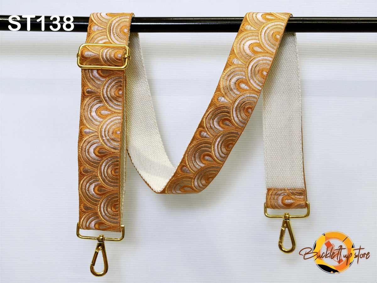 a decorative strap with a gold buckle and a white strap attached to a black bar.
