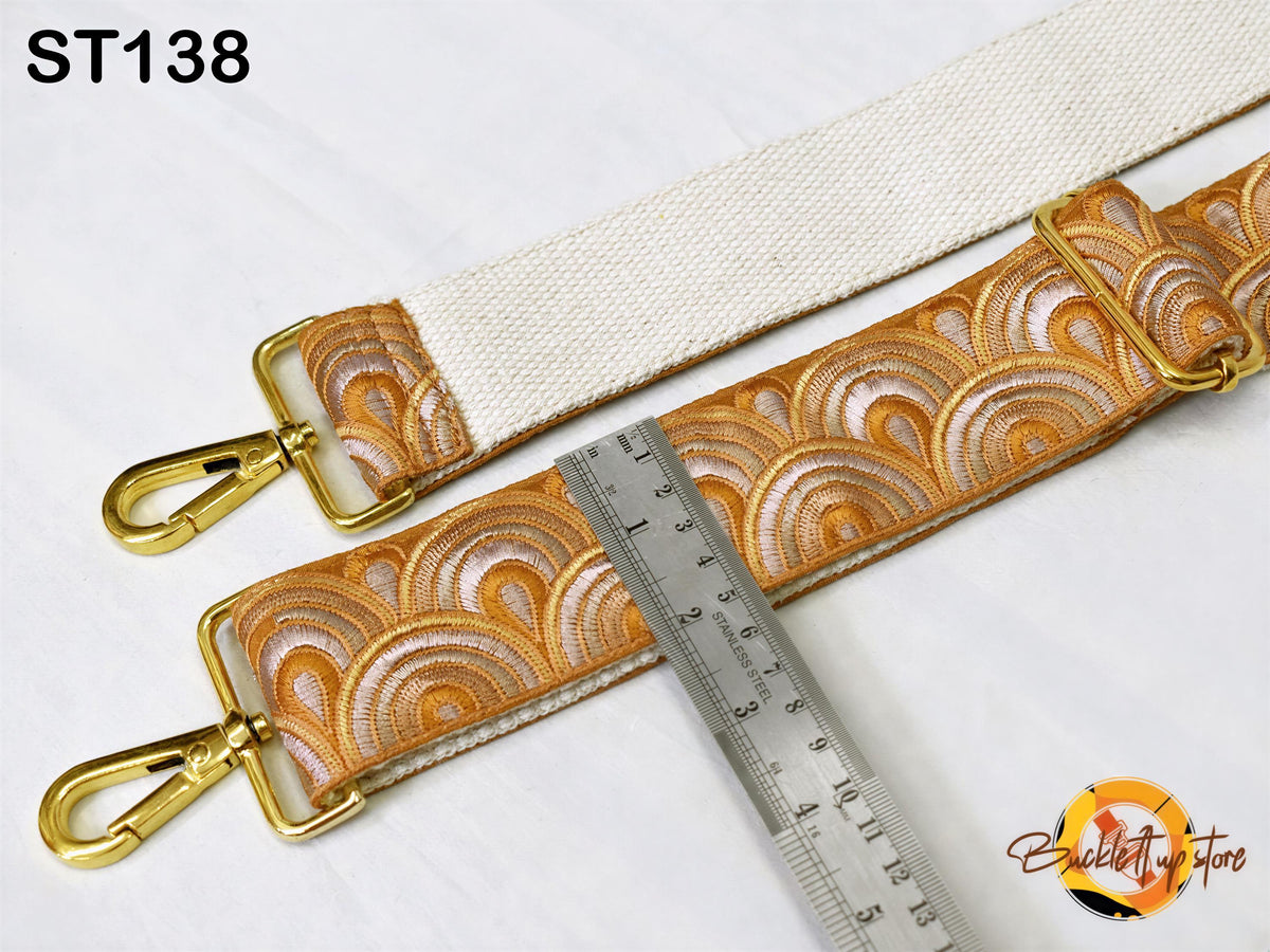 a strap with a gold-colored metal buckle and a ruler placed next to it, indicating the strap's size or length.