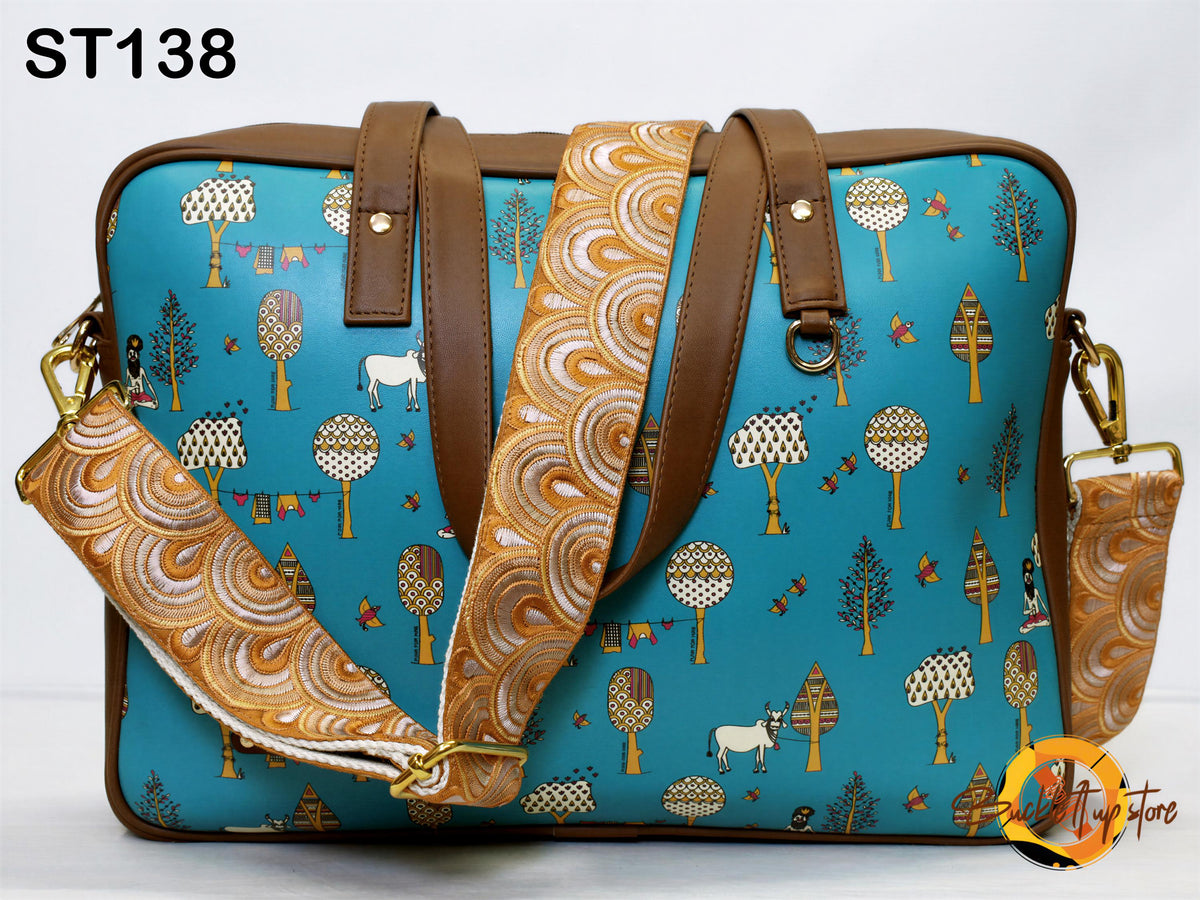 A blue handbag with a pattern of trees, animals, and other decorative elements printed on it. The bag has a brown leather strap and a gold-colored metal clasp.