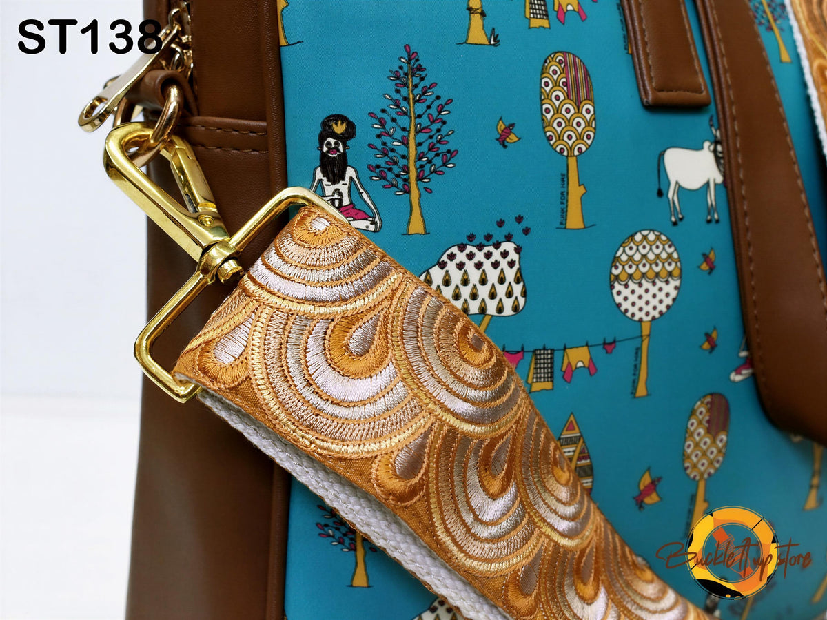 a close-up view of a handbag with a vibrant, colorful pattern featuring various cartoon-like illustrations, including trees, animals, and other whimsical designs. The bag has a brown leather strap and a gold metal clasp, adding a touch of elegance to its overall appearance.