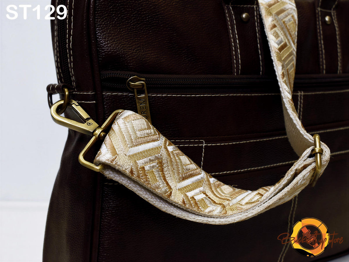 A close-up view of a brown leather bag with a gold-colored strap and zipper.