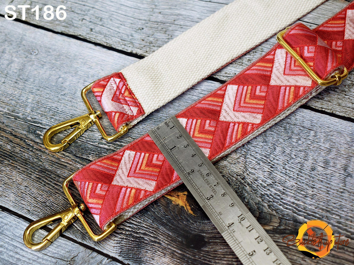 a red and white patterned strap with a metal ruler placed on a wooden surface.
