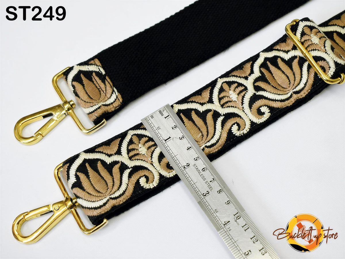 a black strap with a gold-colored floral pattern, and a ruler is placed next to it, indicating the strap's length.