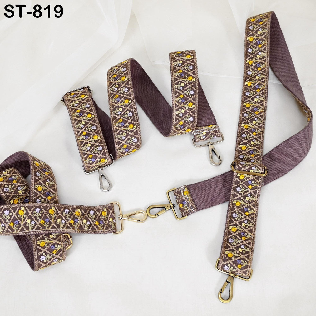 a set of brown and gold embroidered straps with a floral pattern, arranged on a white background.