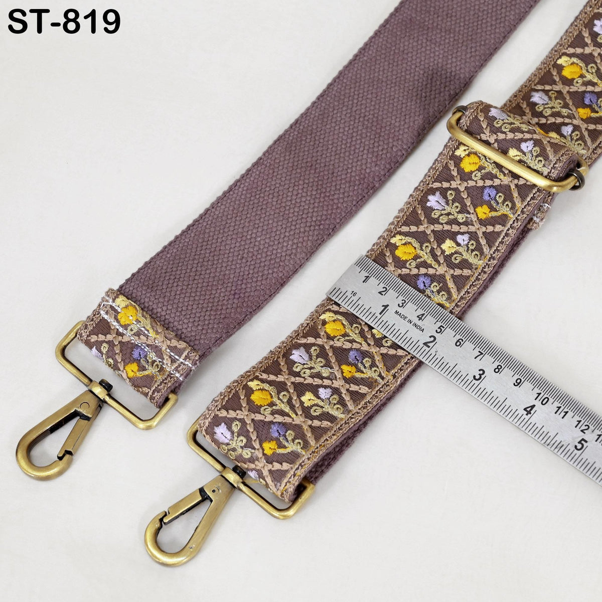 a purple strap with a floral pattern and a metal ruler placed on top of it, indicating the strap's size.