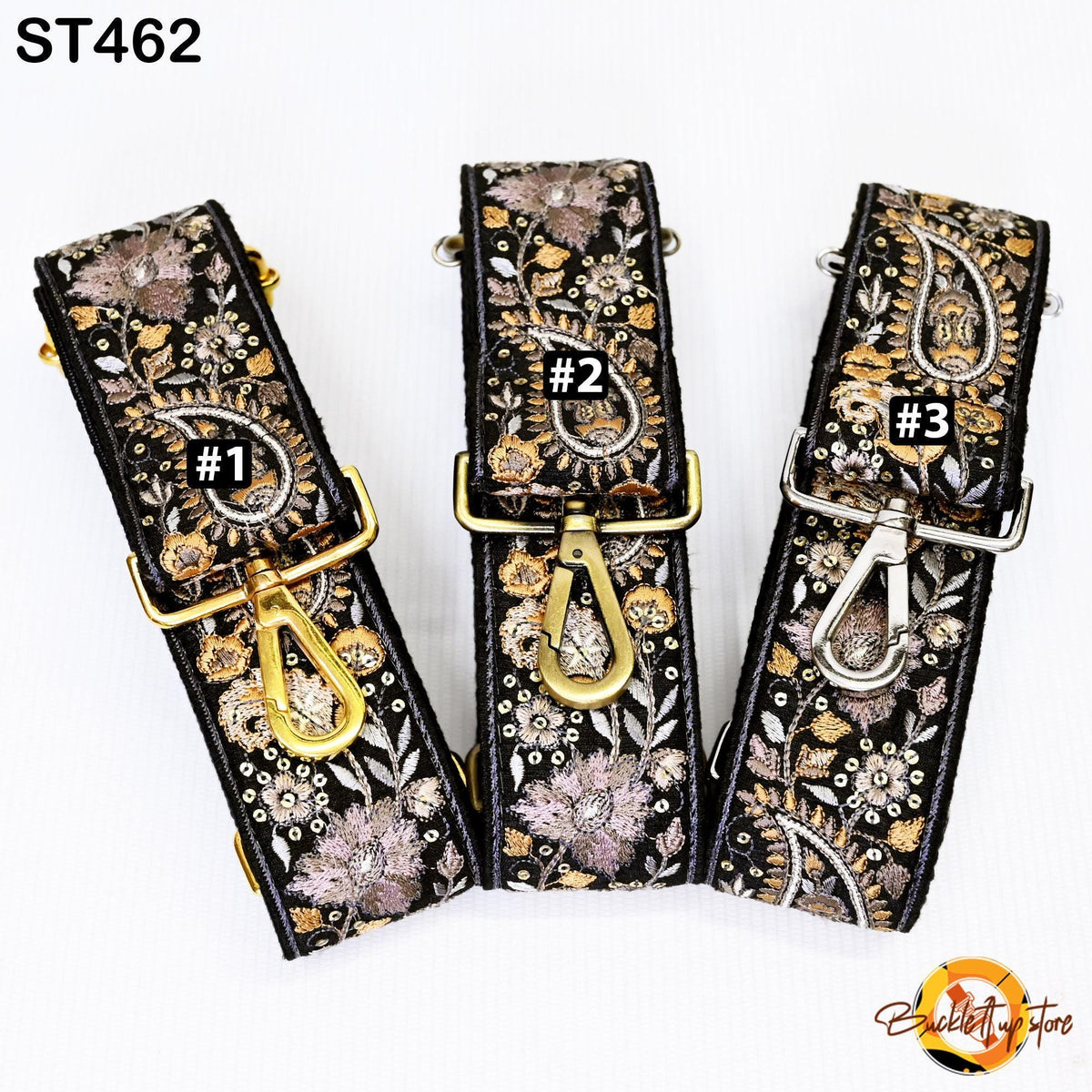 Three black and gold straps with floral patterns, each with a gold clasp and a small black number on it.