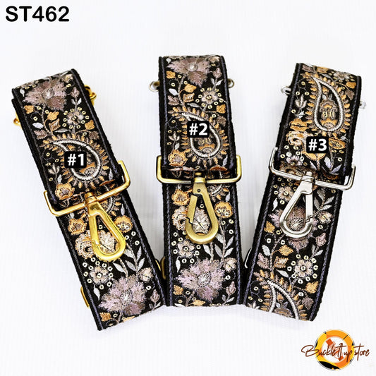 Three black and gold straps with floral patterns, each with a gold clasp and a small black number on it.
