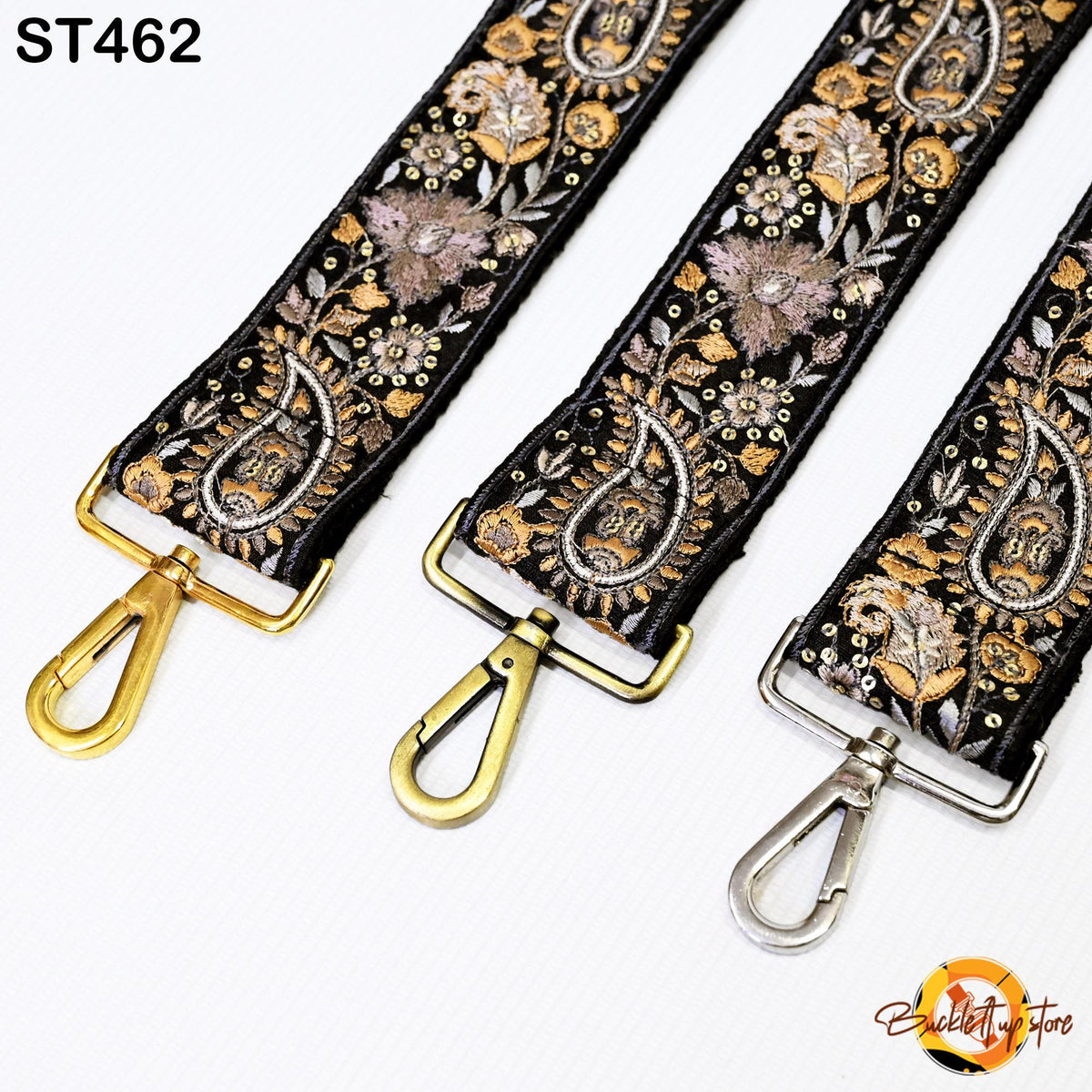 three straps with intricate floral designs in black, gold, and silver colors. The straps have metal hooks at the ends and appear to be made of leather or fabric.