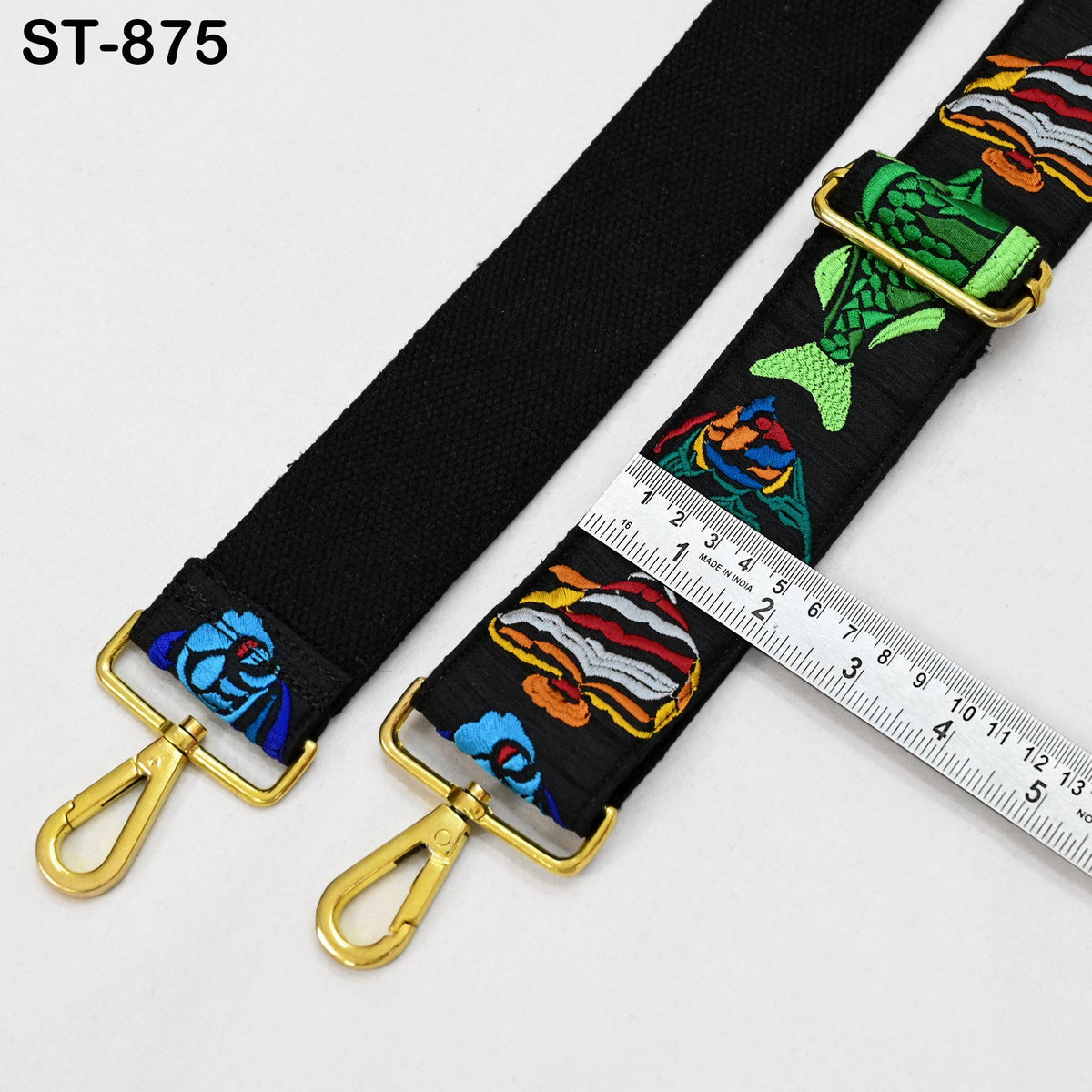 a black strap with colorful fish embroidery, and a ruler is placed next to it, indicating the strap's length.