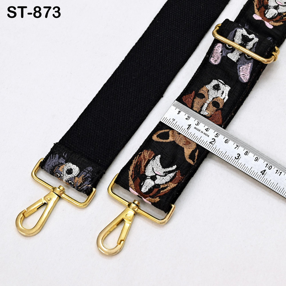 a black strap with a pattern of dog faces on it, and a ruler is placed next to it, indicating the strap's length.