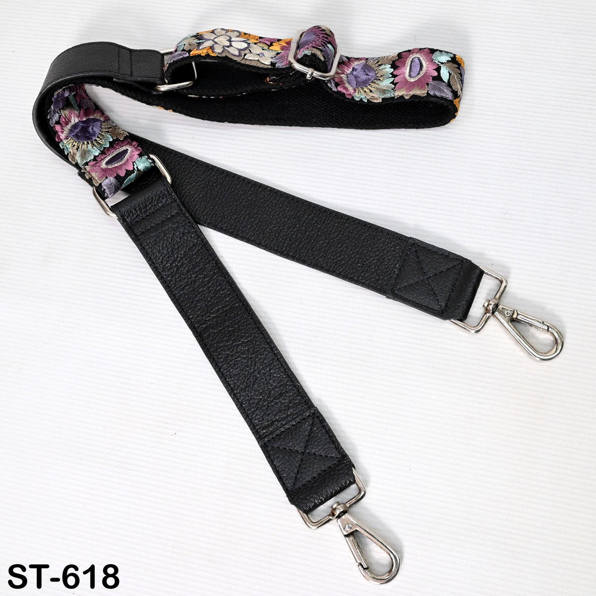A black leather strap with a floral pattern, featuring two metal hooks and a clasp.