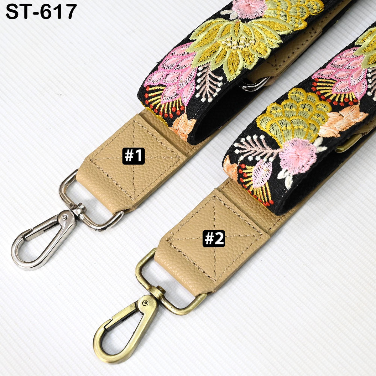 two straps with floral embroidery, one with a beige strap and the other with a black strap. The straps have metal hooks and buckles, and there are small labels on them indicating the number one and two.