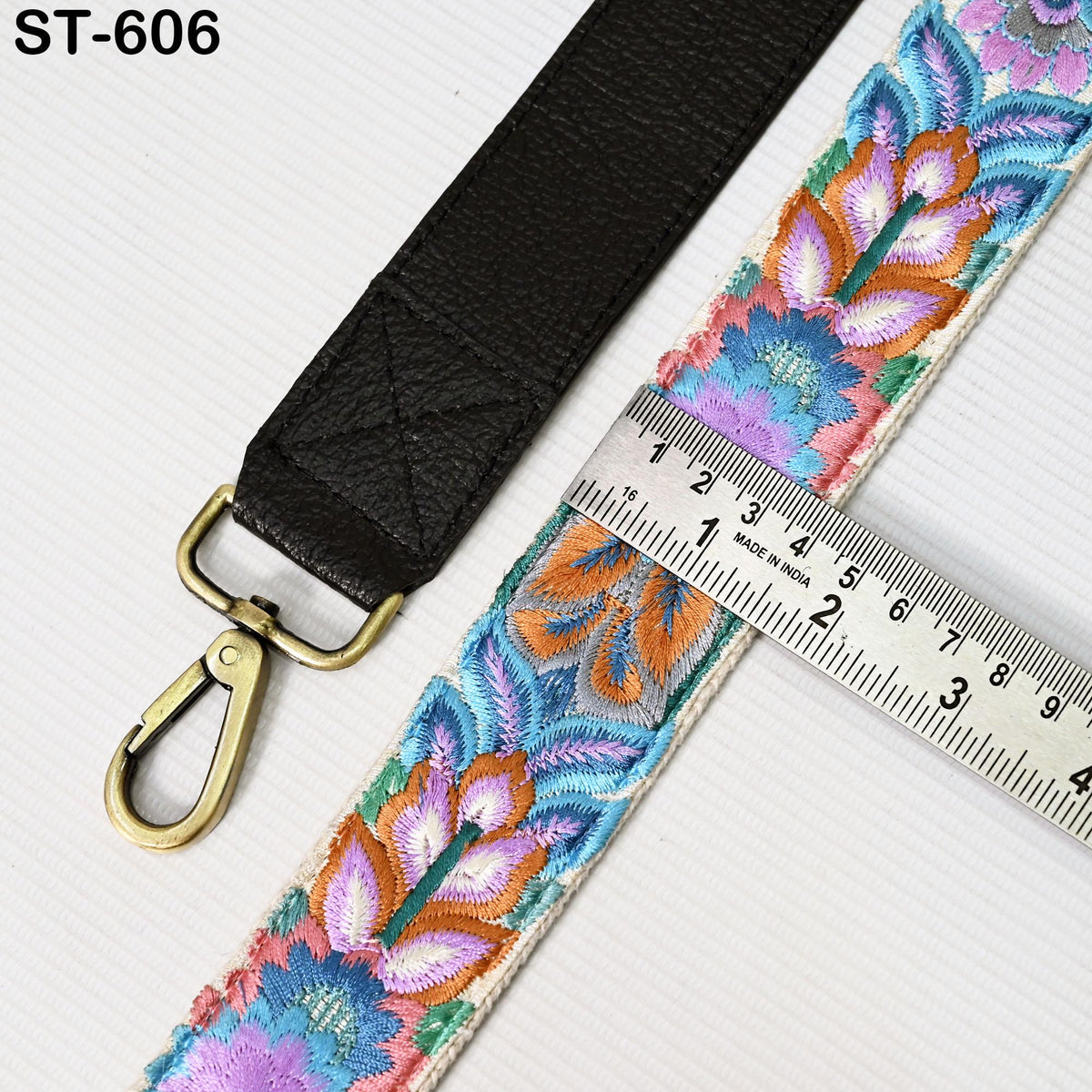 a black leather strap with a floral pattern and a metal ruler placed next to it, indicating the strap's size.