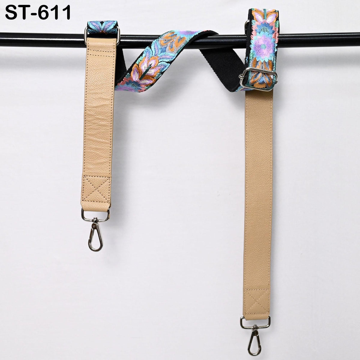 two beige leather straps with colorful floral patterns hanging on a black bar.