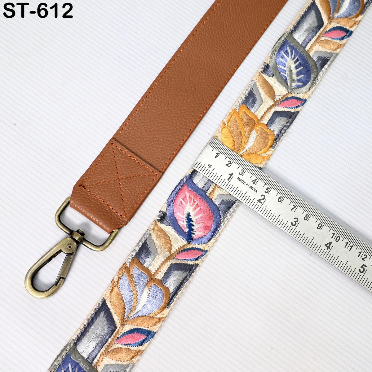 a brown leather strap with a floral pattern, and a ruler is placed next to it, indicating the strap's length.