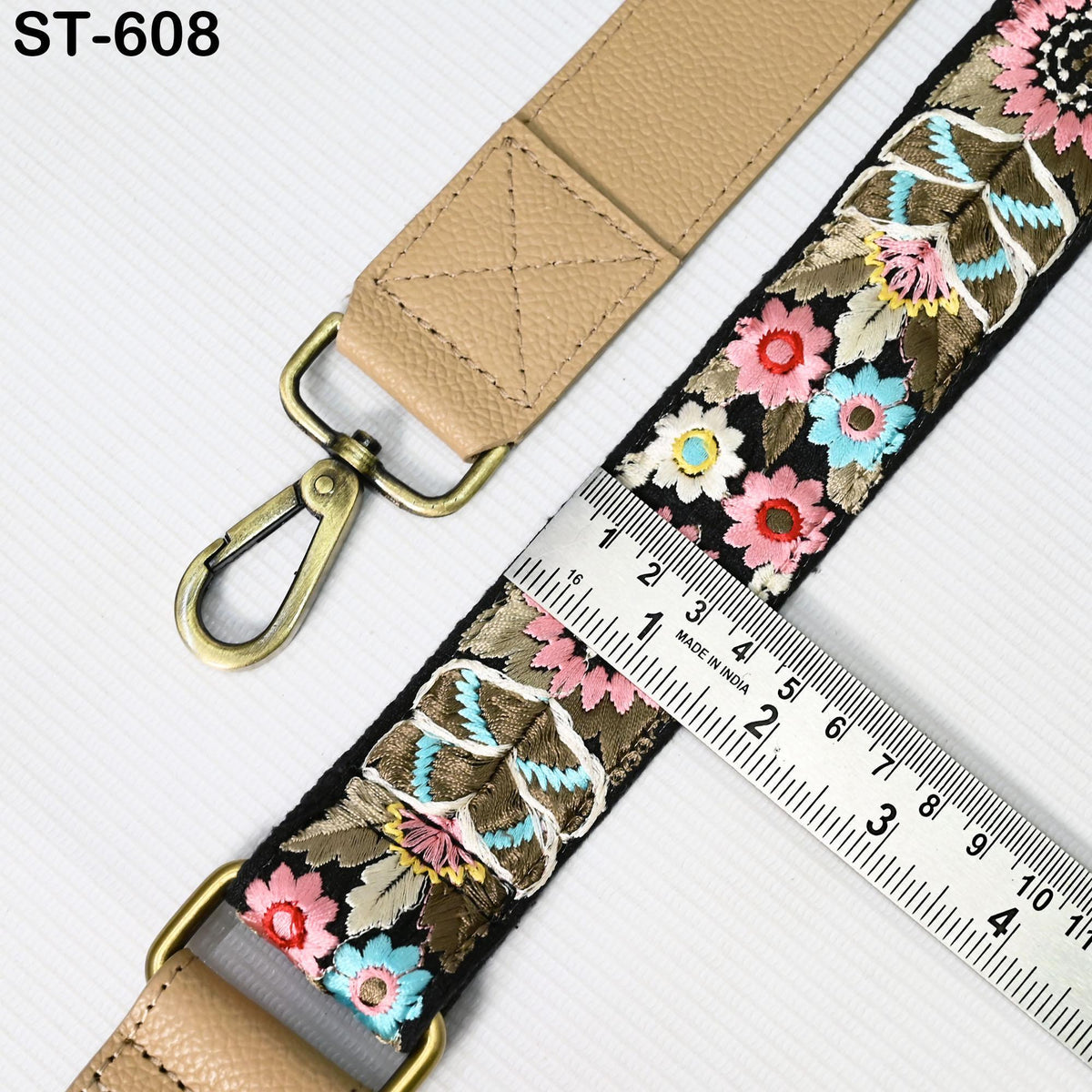 a beige strap with a floral pattern and a metal ruler placed on top of it.