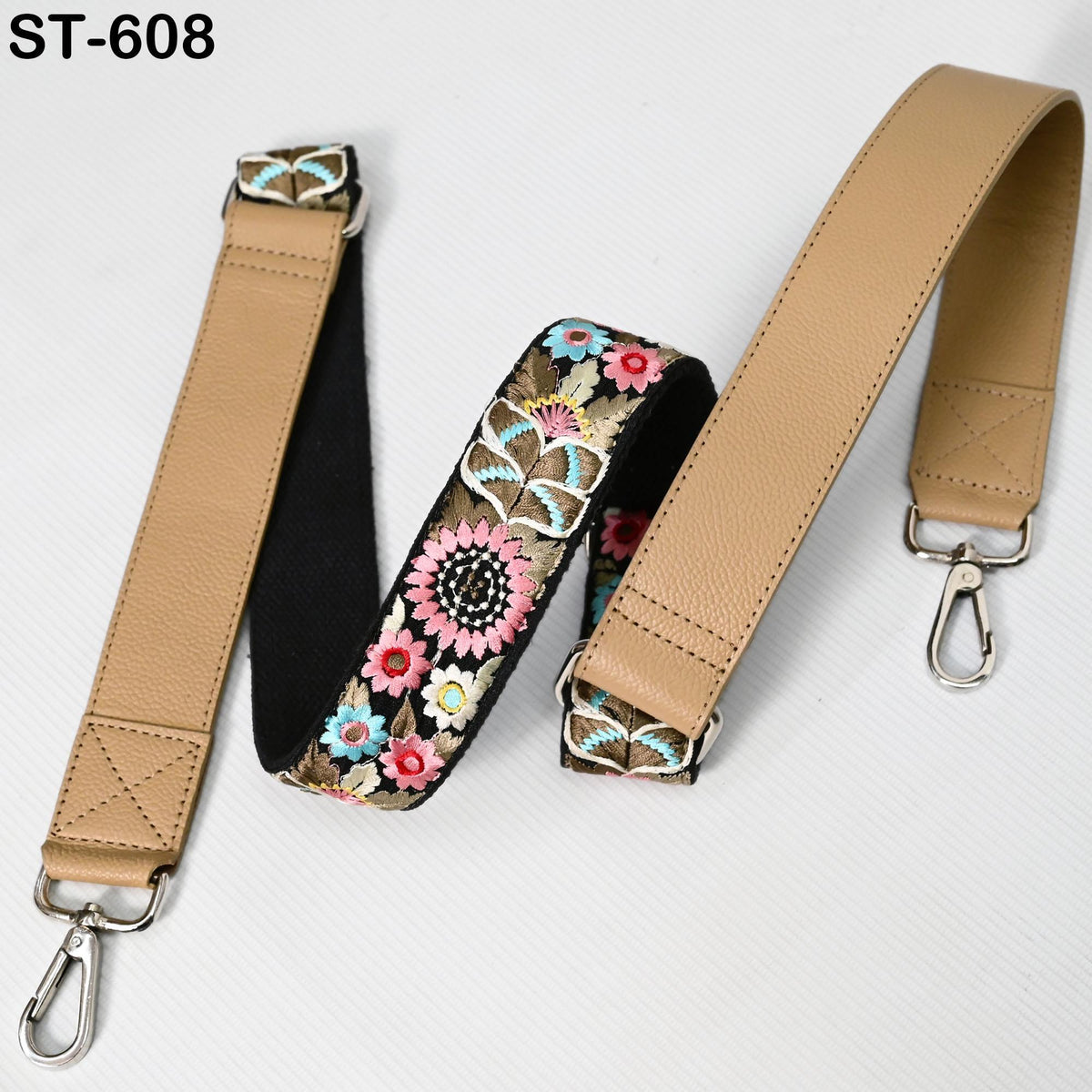 two beige leather straps with floral embroidery, one attached to a leather strap and the other attached to a leather strap.