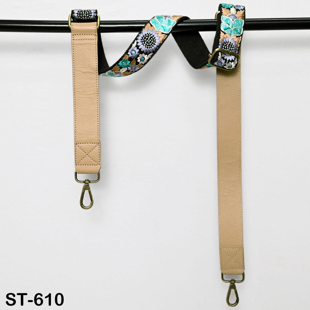 A beige strap with a floral pattern is hanging on a black bar.