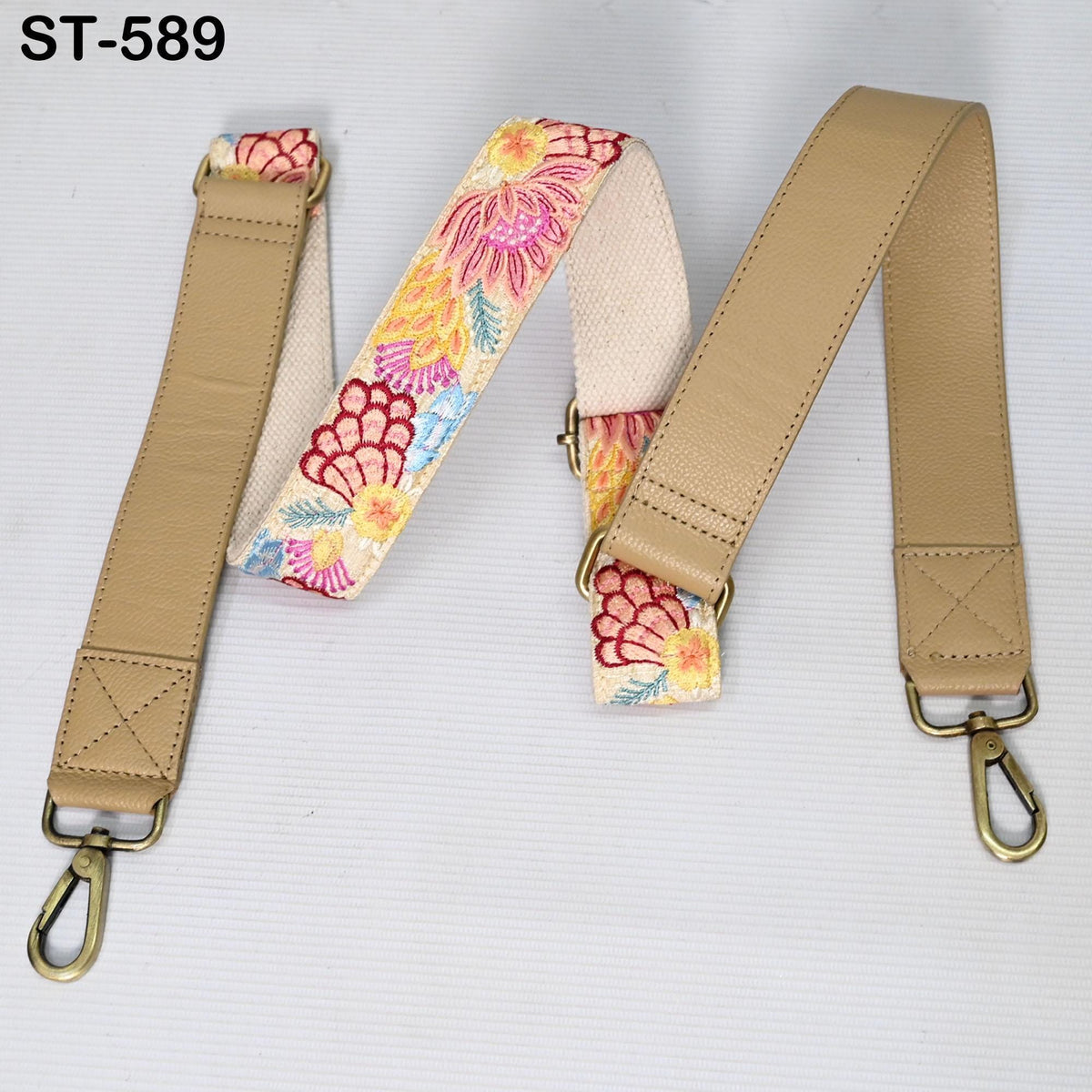 A beige leather strap with a floral pattern, featuring two straps attached to a metal hook.