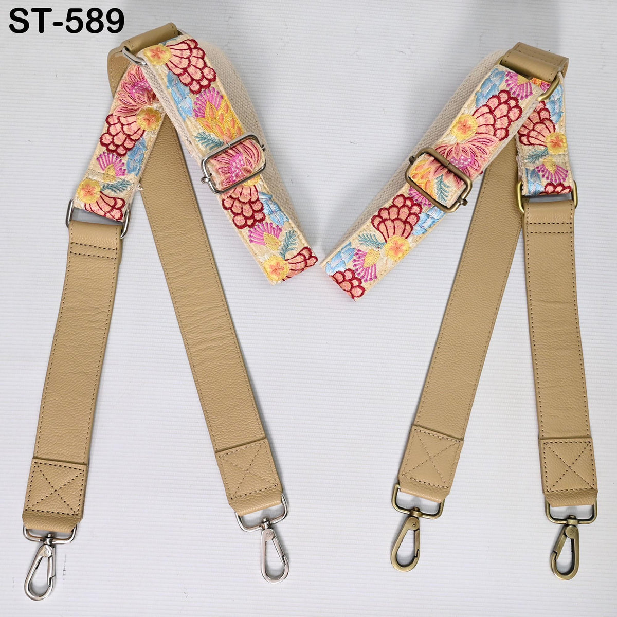 two beige leather straps with floral patterns, each with metal hooks and buckles.
