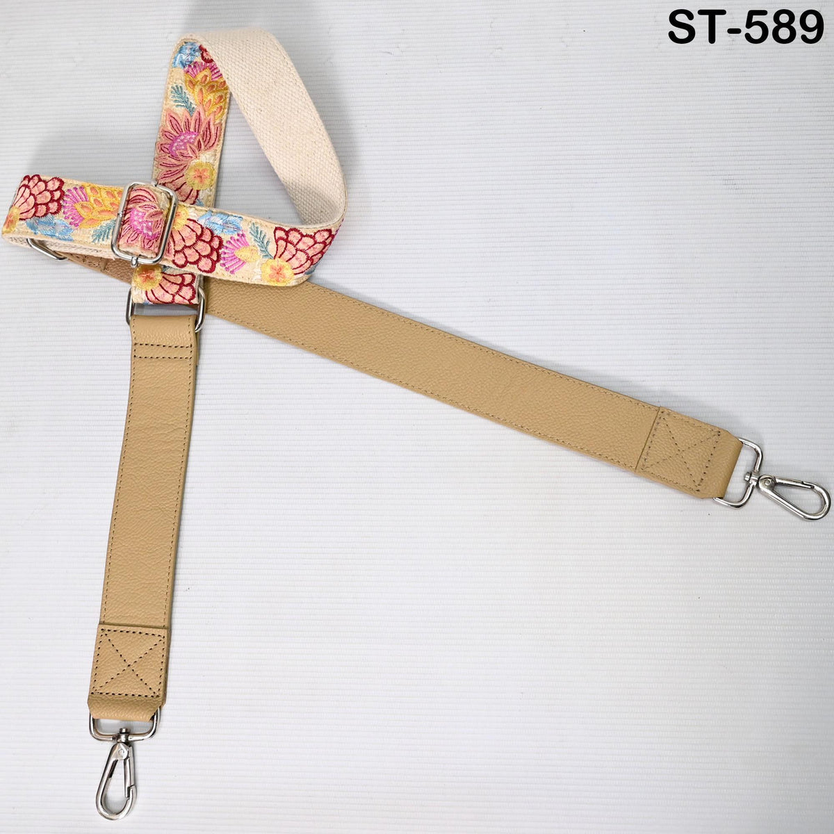 a beige strap with a floral pattern, attached to a metal clasp.