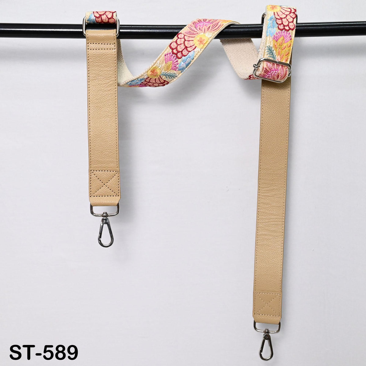 two beige straps with floral patterns hanging on a black bar.