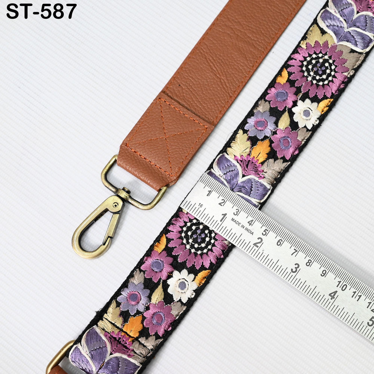 a brown leather strap with a floral pattern and a metal ruler placed next to it, indicating the strap's size.