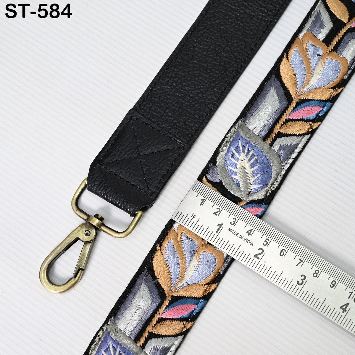 a black leather strap with a metal clasp and a ruler placed on top of it, indicating the strap's length.