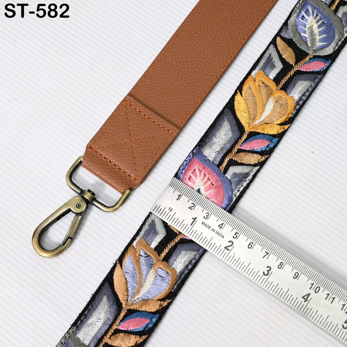 a brown leather strap with a floral pattern and a metal ruler placed next to it, indicating the strap's length.