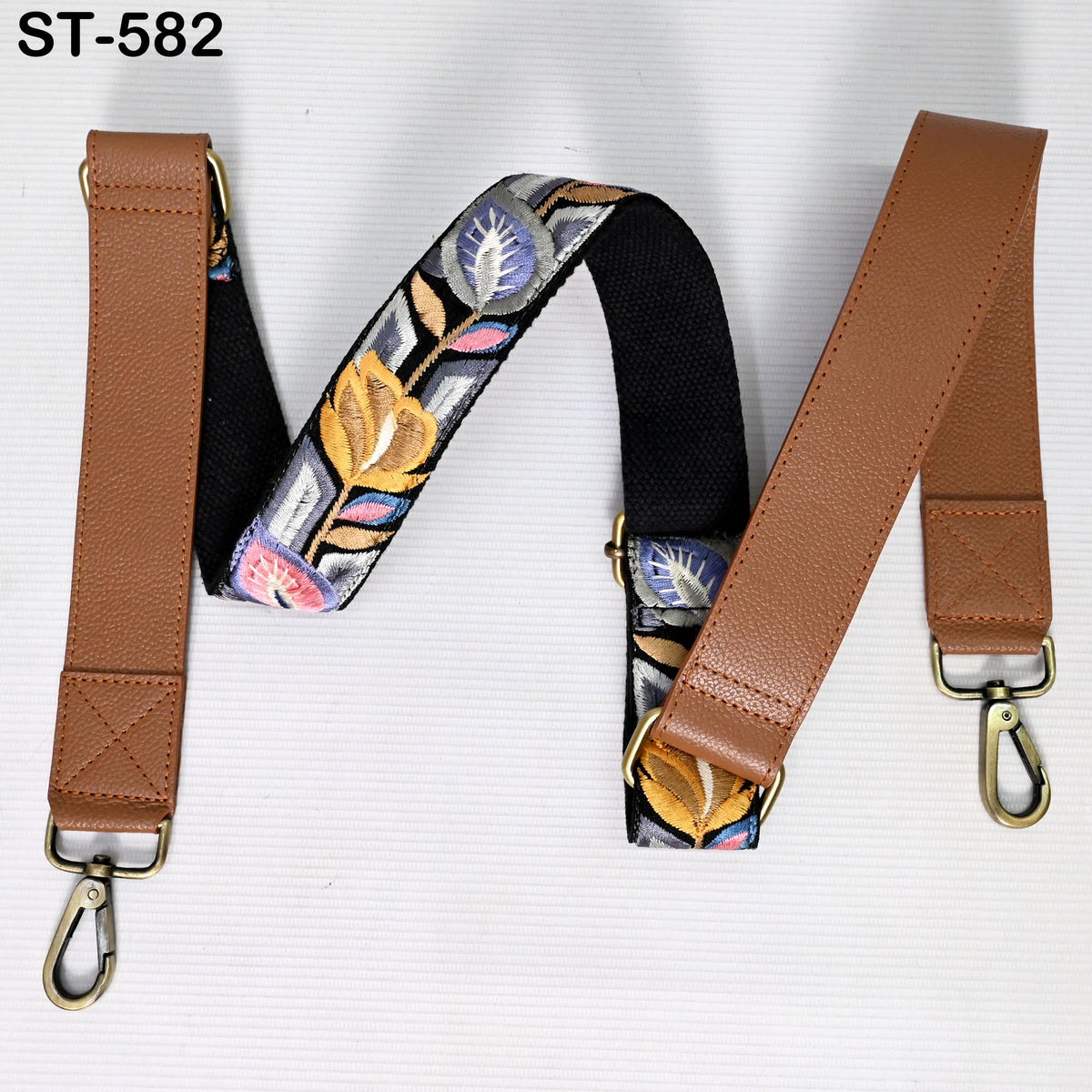 a pair of leather straps with floral embroidery, one brown and one black, attached to a white background.