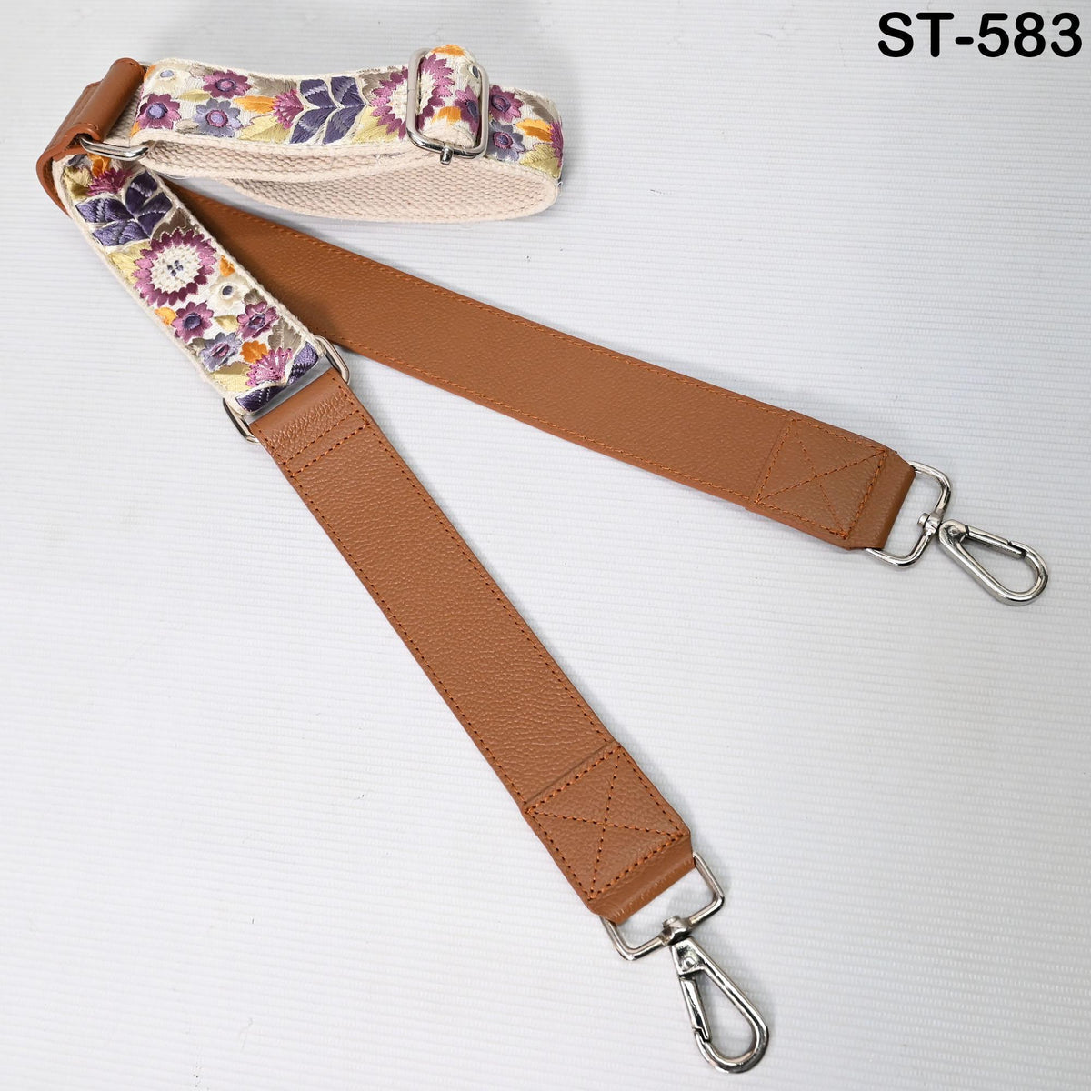 a brown leather strap with a floral pattern, which appears to be a strap for a bag or accessory.