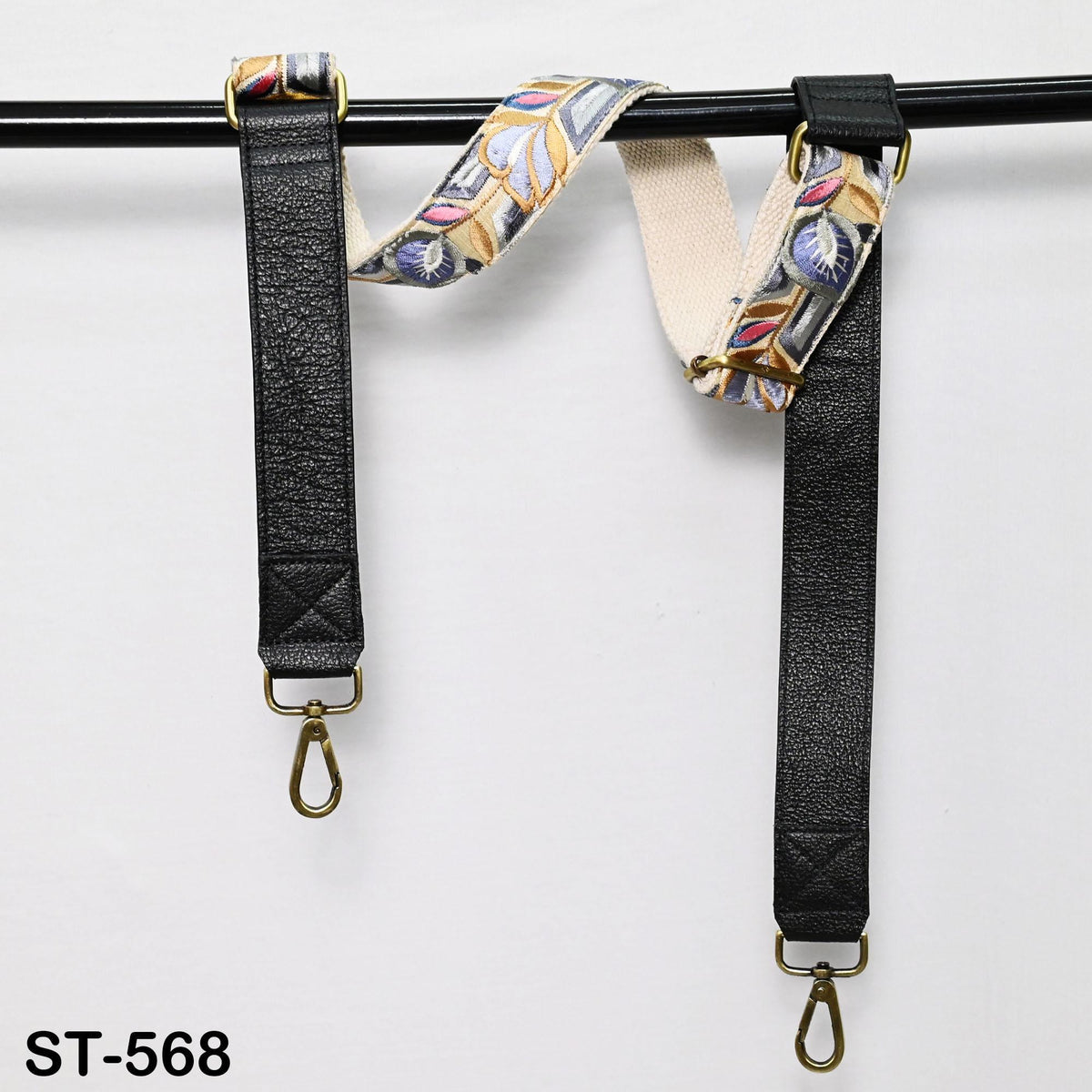 two black leather straps with gold hardware, hanging on a black bar.