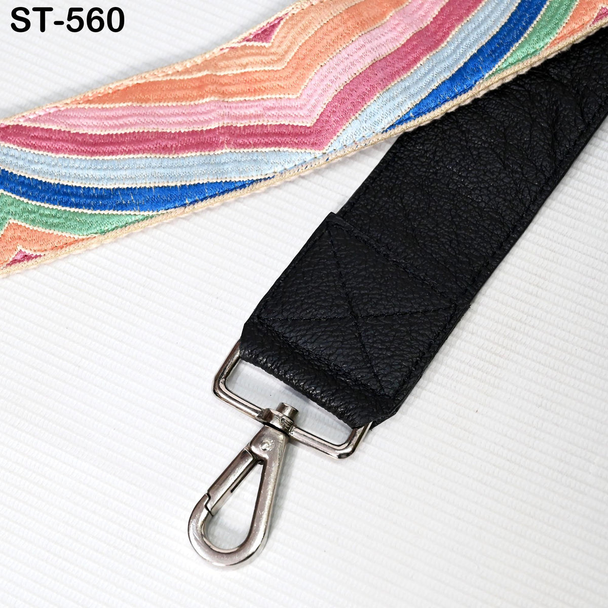 A black leather strap with a metal hook and a colorful, striped fabric on a white background.