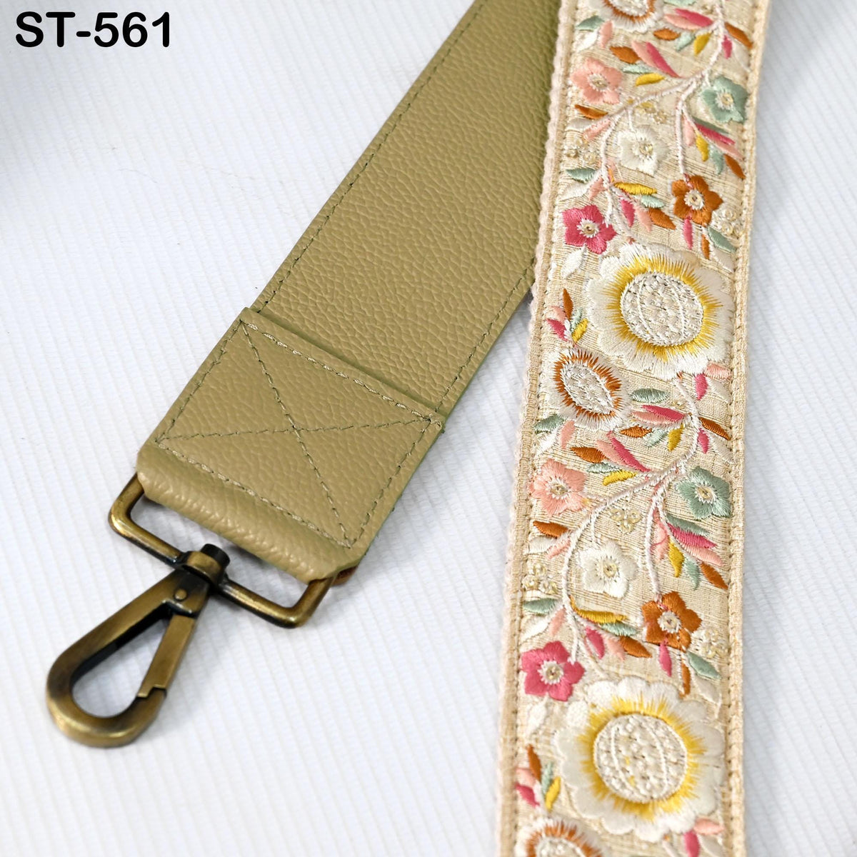 A beige leather strap with a floral embroidered pattern and a metal clasp.