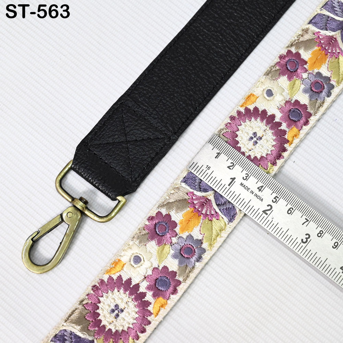 a black leather strap with a floral pattern and a ruler placed next to it, indicating the strap's size.