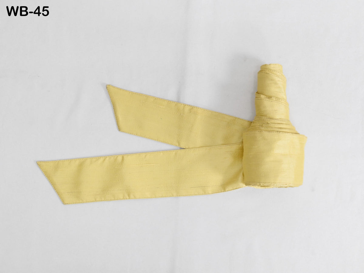 a yellow ribbon or fabric item, possibly a decorative piece or accessory, lying on a white background.