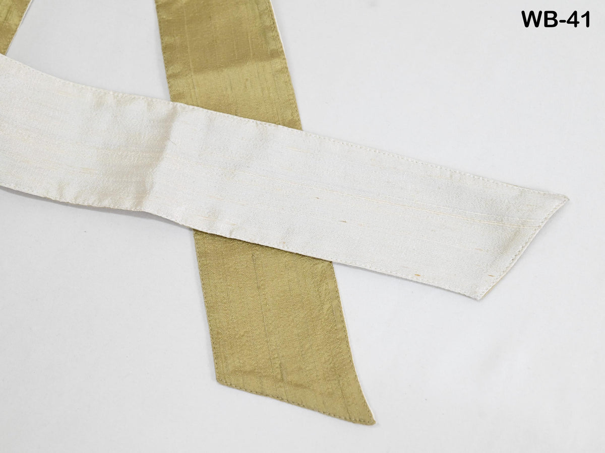 a close-up view of a white and gold ribbon or fabric, with the gold ribbon appearing to be slightly curled and overlapping the white ribbon.