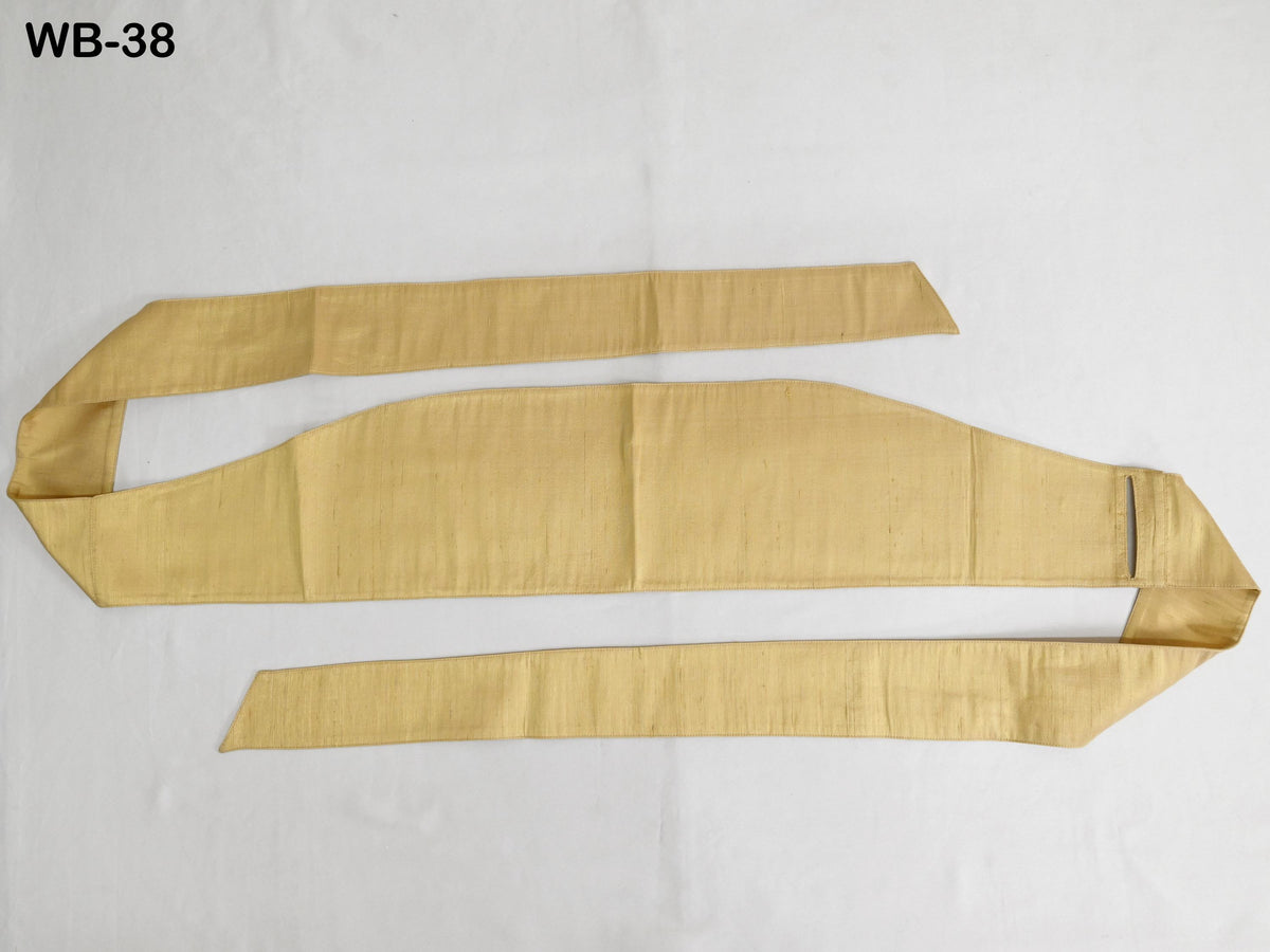 a gold-colored sash or belt lying on a white surface.
