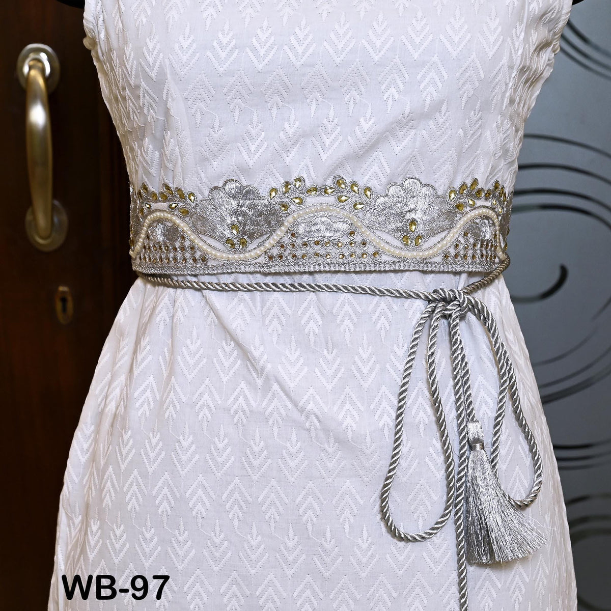 A white dress with a decorative belt and tassel.