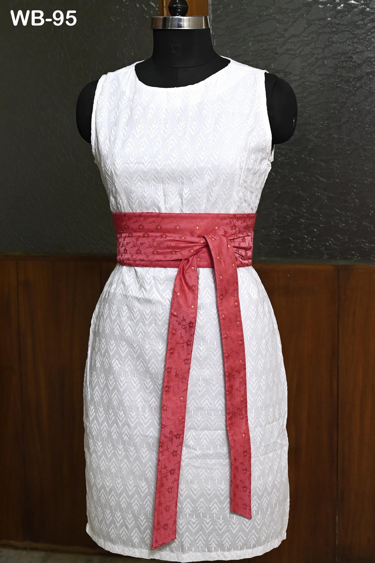 A white dress with a red belt, displayed on a mannequin.