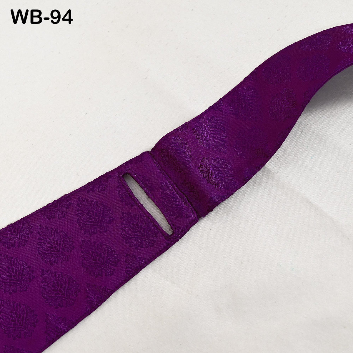 A close-up view of a purple fabric with a floral pattern, lying on a white surface.